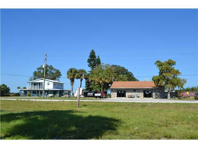 A two-story house and a single-story stone building sit behind a grassy field — 6275 Us Highway 441 SE, Okeechobee FL 34974, OKEECHOBEE, FL
