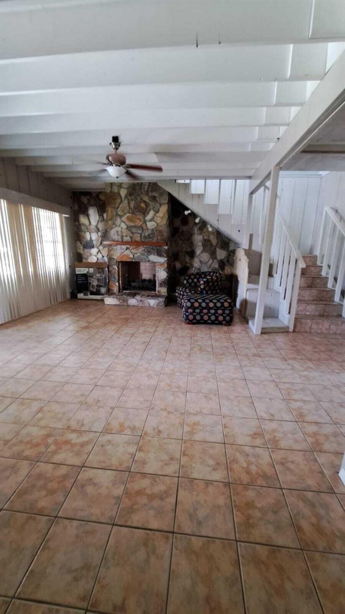 A living room features a stone fireplace, tiled floors, and a staircase with white railings — 6275 Us Highway 441 SE, Okeechobee FL 34974, OKEECHOBEE, FL