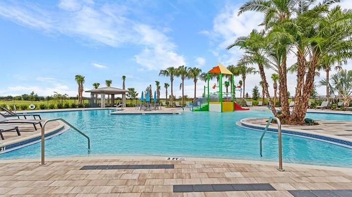 A swimming pool with a colorful water play structure and palm trees under a blue sky — 315 CASTLEVIEW DRIVE, DAVENPORT, FL