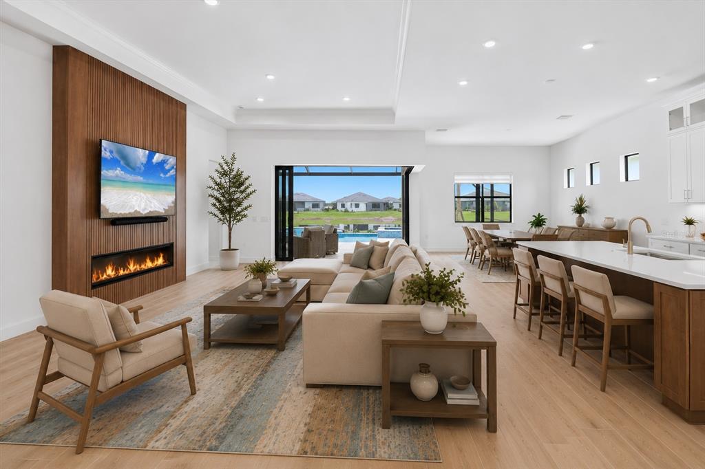 An open-concept living room features a wood-paneled fireplace wall, a large sectional, and kitchen island — 4923 EMPIRE LANDING RUN, BRADENTON, FL