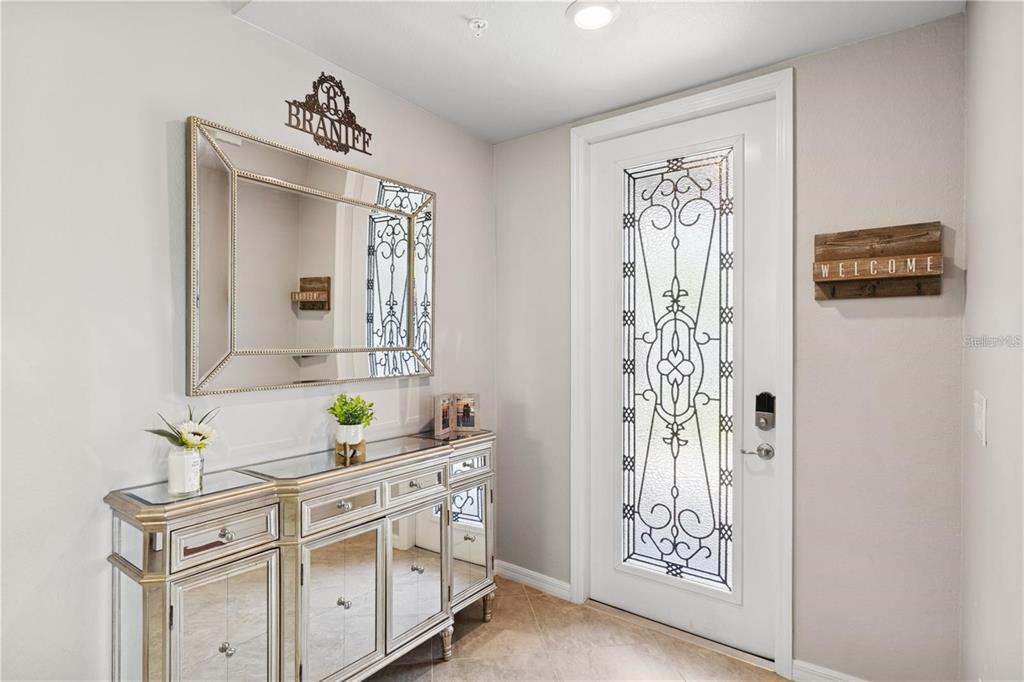 A mirrored console table and wall mirror sit in a foyer with a glass-paneled door — 917 TIDEWATER SHORES LOOP, BRADENTON, FL