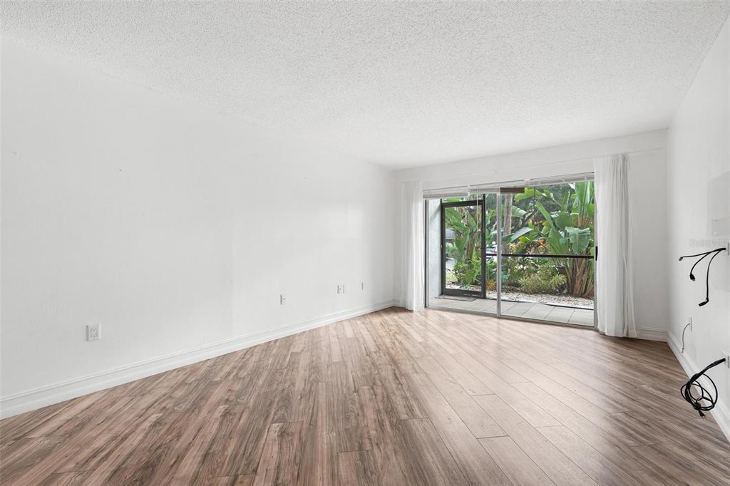 An empty room with wood-look flooring, white walls, and a sliding glass door to outdoors — 3223 BENEVA ROAD UNIT 101, SARASOTA, FL