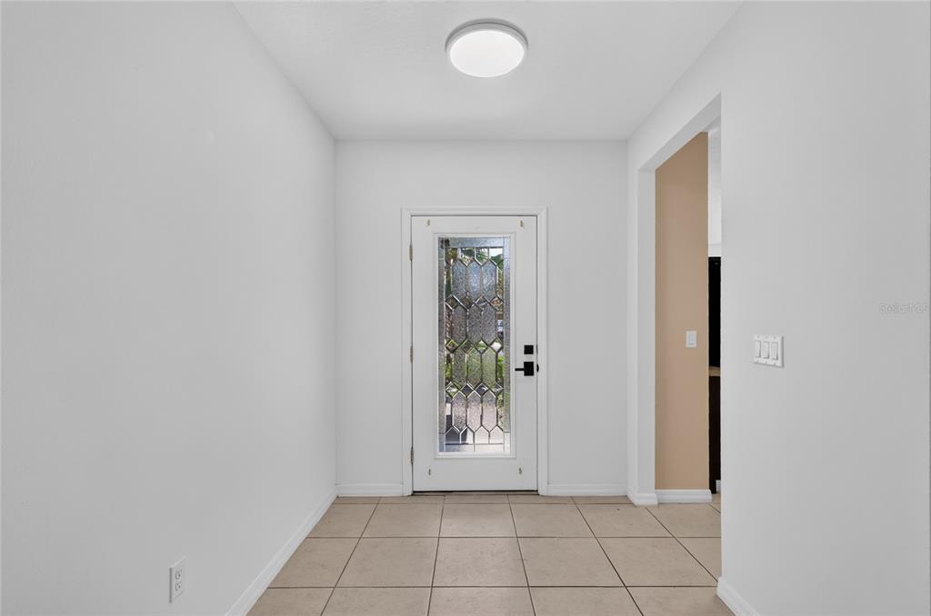 An entryway features white walls, tile flooring, a flush-mount ceiling light, and a glass-paneled door — 345 RED KITE DRIVE, GROVELAND, FL