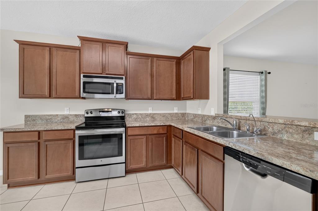 A kitchen with wood cabinets, stainless steel appliances, and granite countertops — 345 RED KITE DRIVE, GROVELAND, FL