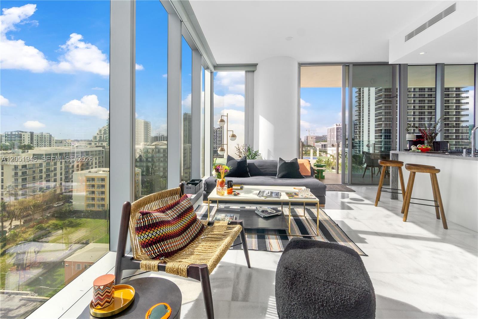 A modern living room features floor-to-ceiling windows, white marble floors, and a balcony view — 700 NE 26th Ter # 1005, Miami FL 33137, MIAMI, FL