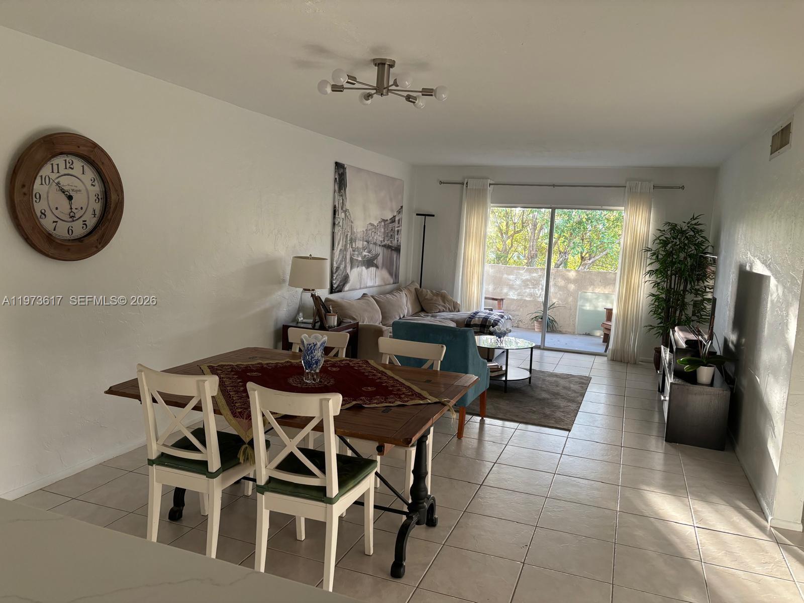 A living and dining area features tile floors, a wooden table, and a sliding glass door — 6884 N Kendall Dr # C407, Pinecrest FL 33156, PINECREST, FL