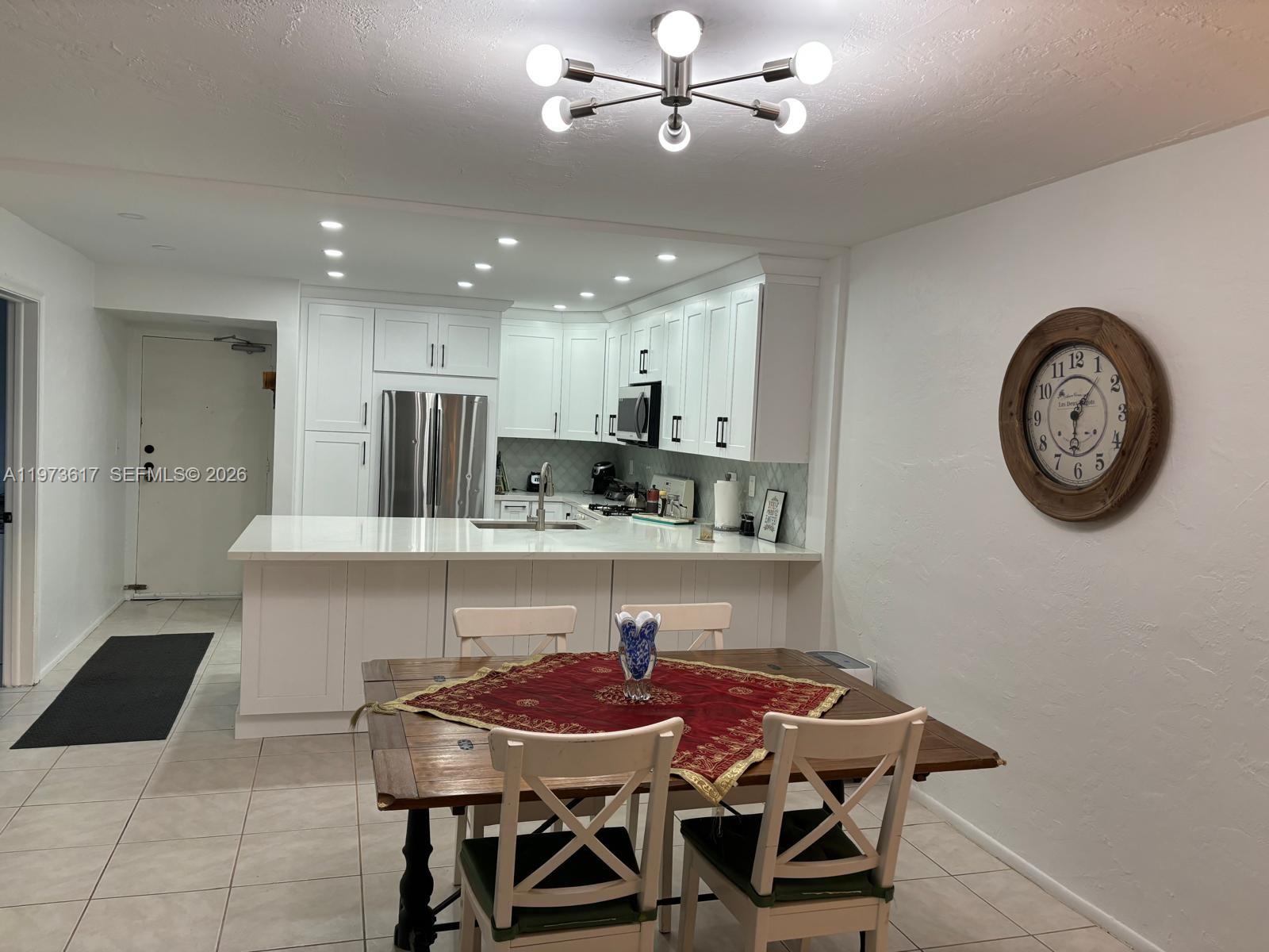 A kitchen with white cabinets and a quartz island opens into a dining area — 6884 N Kendall Dr # C407, Pinecrest FL 33156, PINECREST, FL