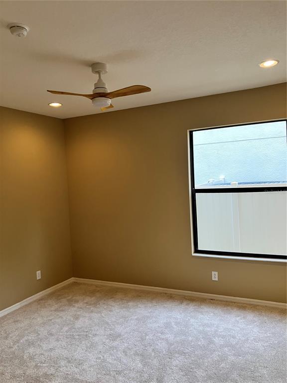 An empty bedroom features beige walls, light-colored carpet, a ceiling fan, and a single window — 15041 PRINCEWOOD LANE, LAND O LAKES, FL