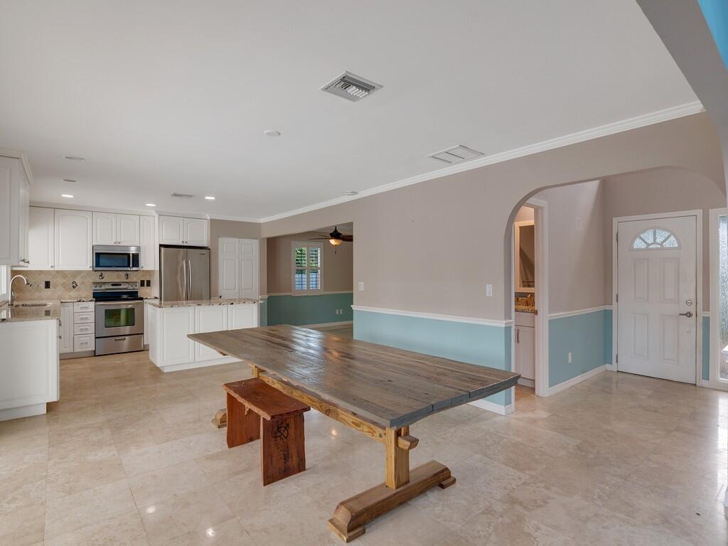 A kitchen and dining area with white cabinets, a wooden table, and light-colored tile floors — 721 Shore Drive, Vero Beach FL 32963, VERO BEACH, FL