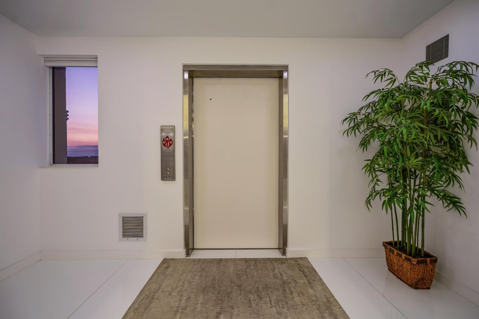 An elevator door sits between a window with a sunset view and a potted plant — 2150 N Ocean Blvd, Boca Raton FL 33431, BOCA RATON, FL