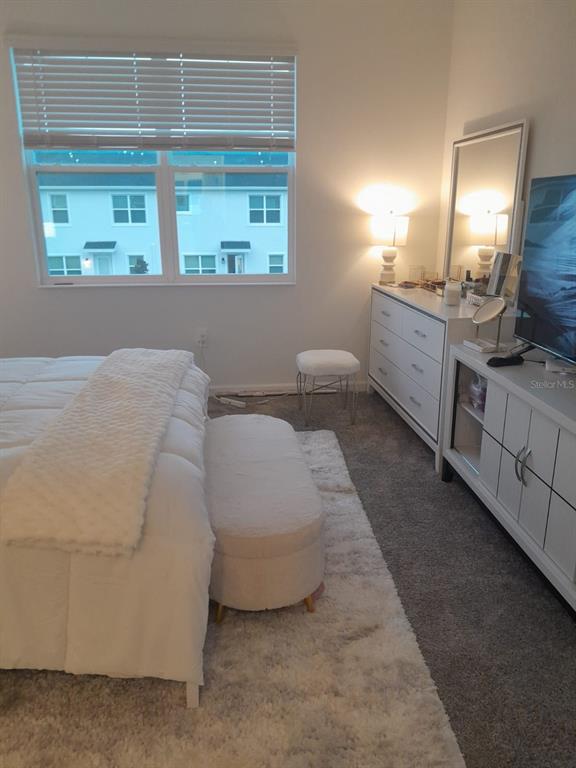 A bedroom features a white bed, a matching dresser with a mirror, and a window — 113 BOGEY DRIVE, DAVENPORT, FL
