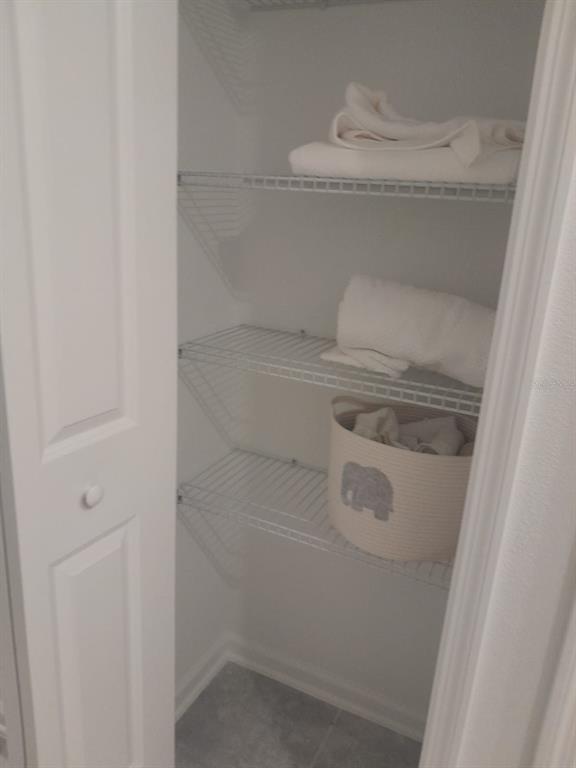 A white closet features wire shelving holding folded towels and a basket with an elephant design — 113 BOGEY DRIVE, DAVENPORT, FL
