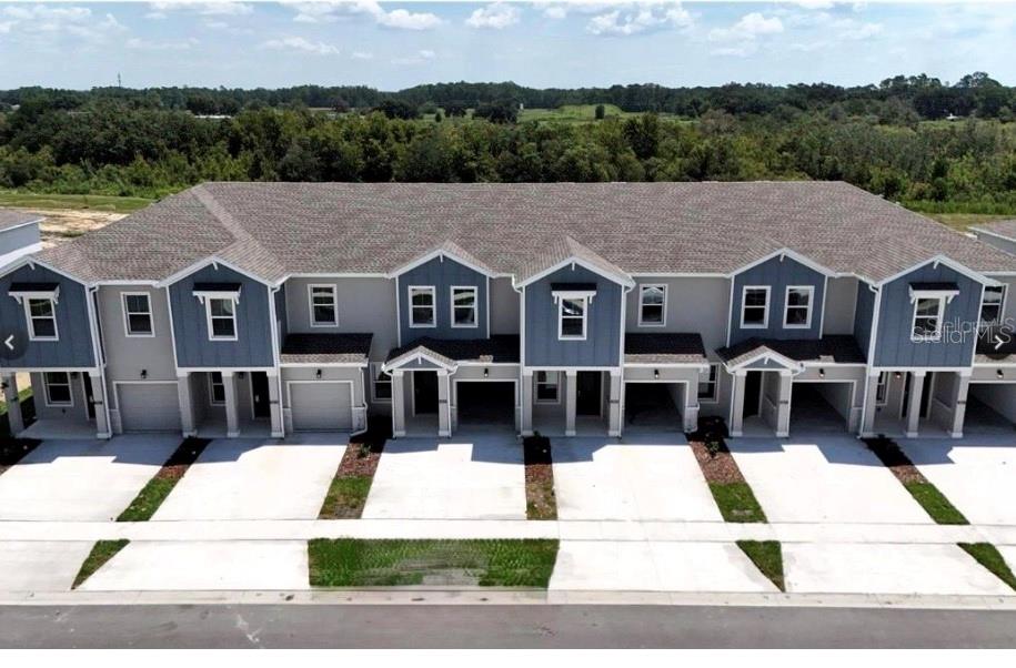 An exterior view of a multi-unit townhouse building with blue siding and concrete driveways — 2837 PIERR STREET, DAVENPORT, FL