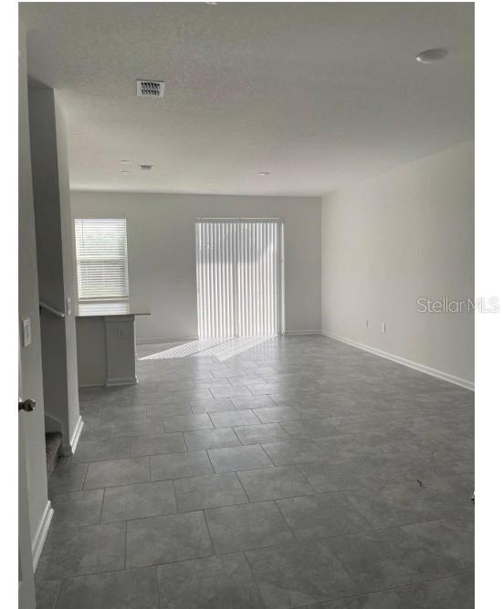 An open-concept living area features gray tile flooring, recessed lighting, and a sliding glass door — 2837 PIERR STREET, DAVENPORT, FL