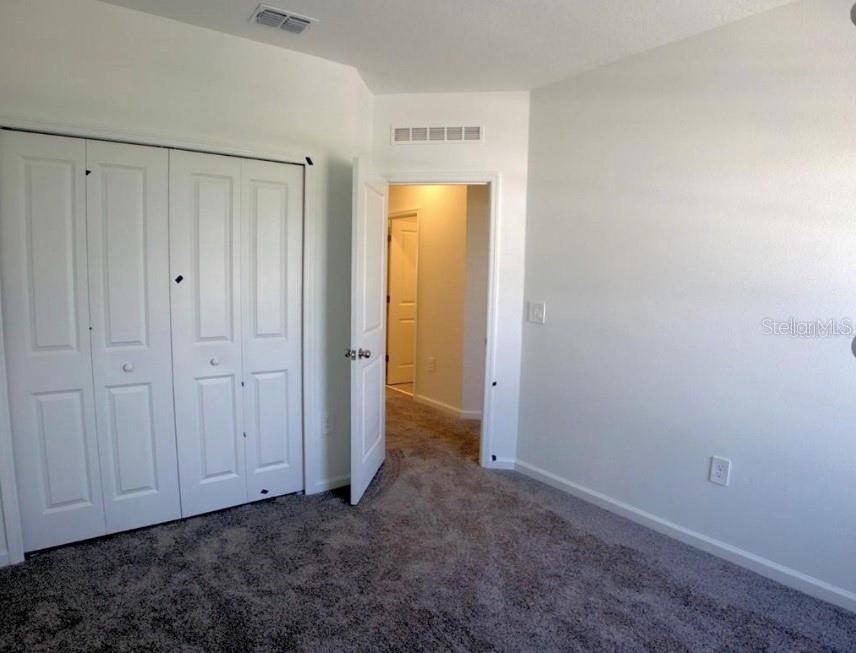 A bedroom with gray carpet, white walls, a white closet, and an open doorway — 2837 PIERR STREET, DAVENPORT, FL
