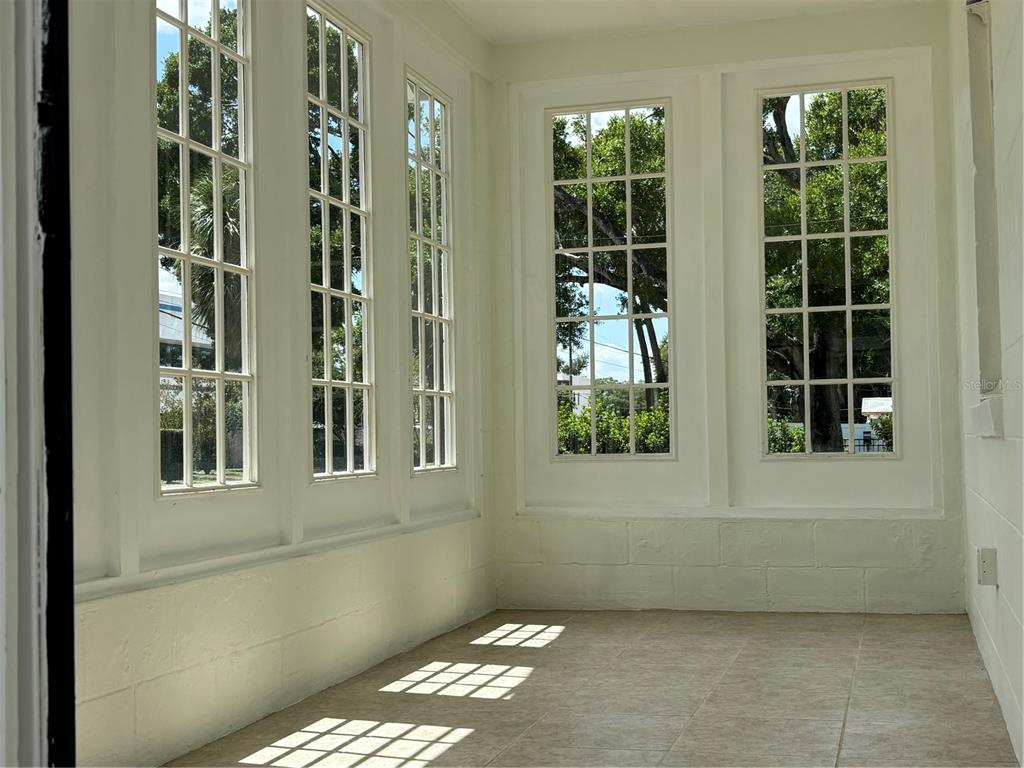 A sunroom with tiled floors, white painted block walls, and multiple tall, multi-pane windows — 3211 W NORTH A STREET, TAMPA, FL