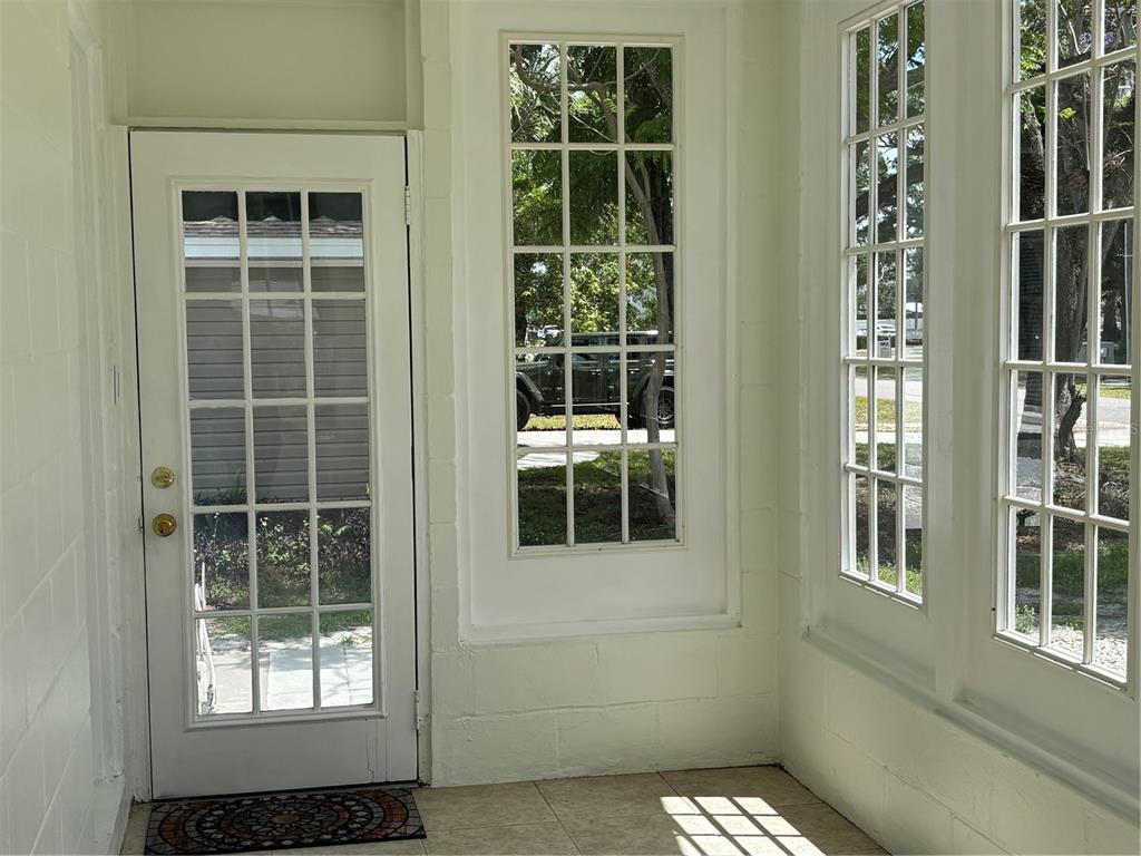 A sunroom with a white door, large windows, and light-colored tile flooring — 3211 W NORTH A STREET, TAMPA, FL