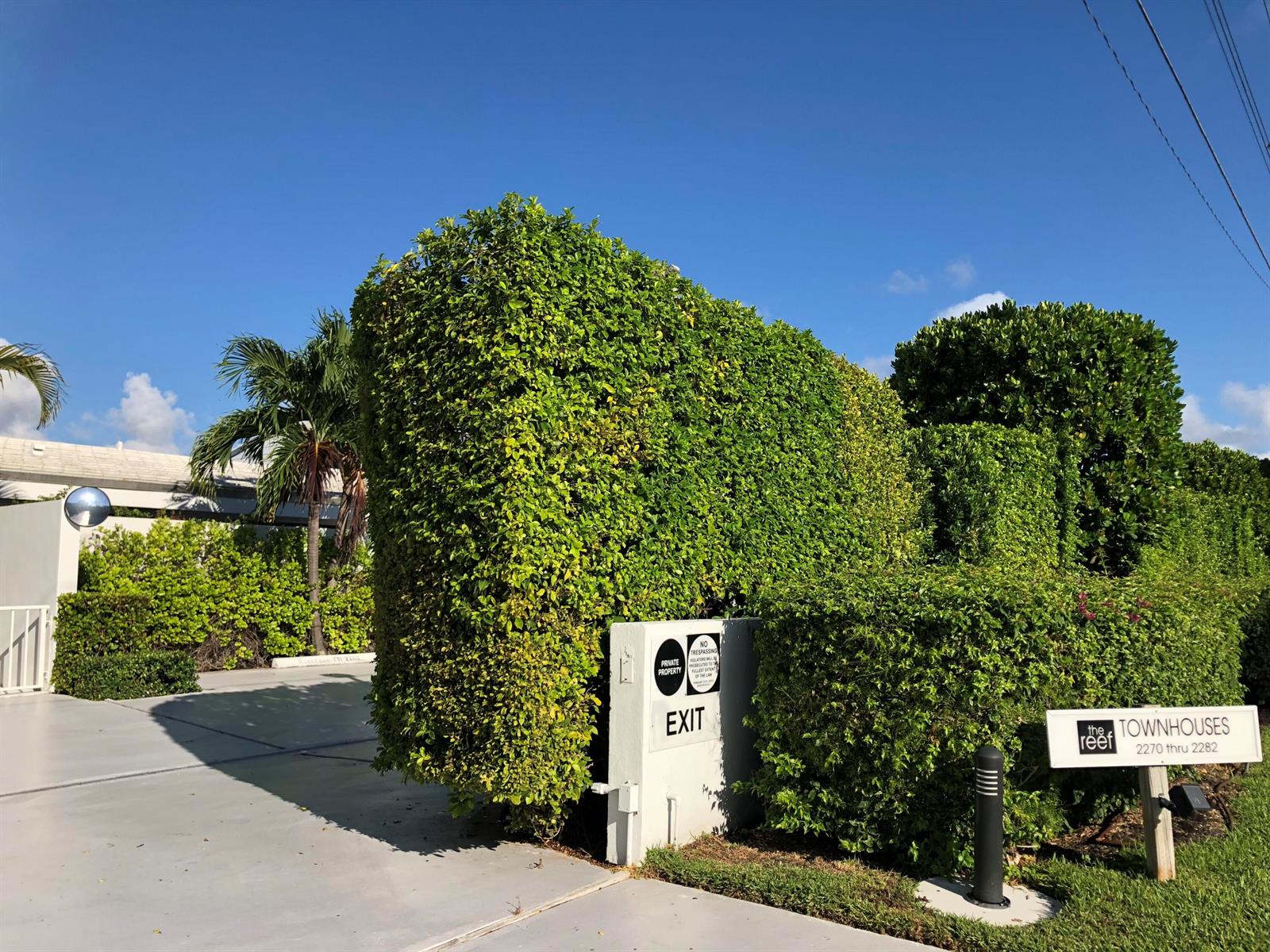 A paved driveway leads to an exit sign beside a large, manicured hedge — 2272 S Ocean Boulevard # T6, Palm Beach FL 33480, PALM BEACH, FL