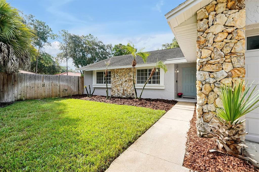 A single-story house exterior features a stone facade, a light blue front door, and landscaping — 8405 WAIALAE COURT, ORLANDO, FL