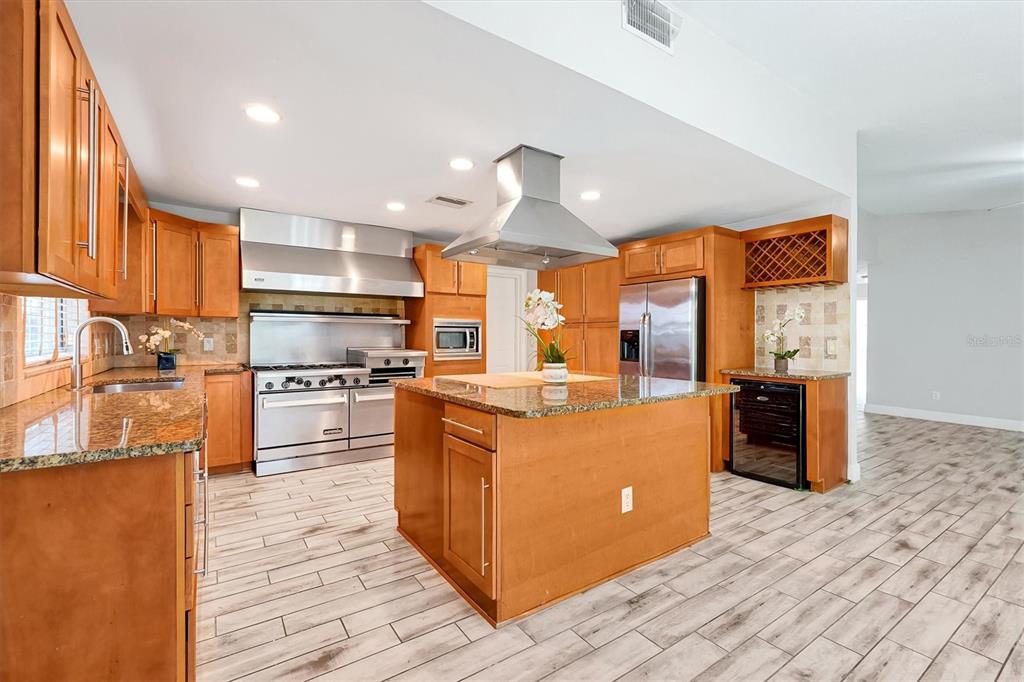 A kitchen with wood cabinets, granite countertops, a center island, and stainless steel appliances — 8405 WAIALAE COURT, ORLANDO, FL