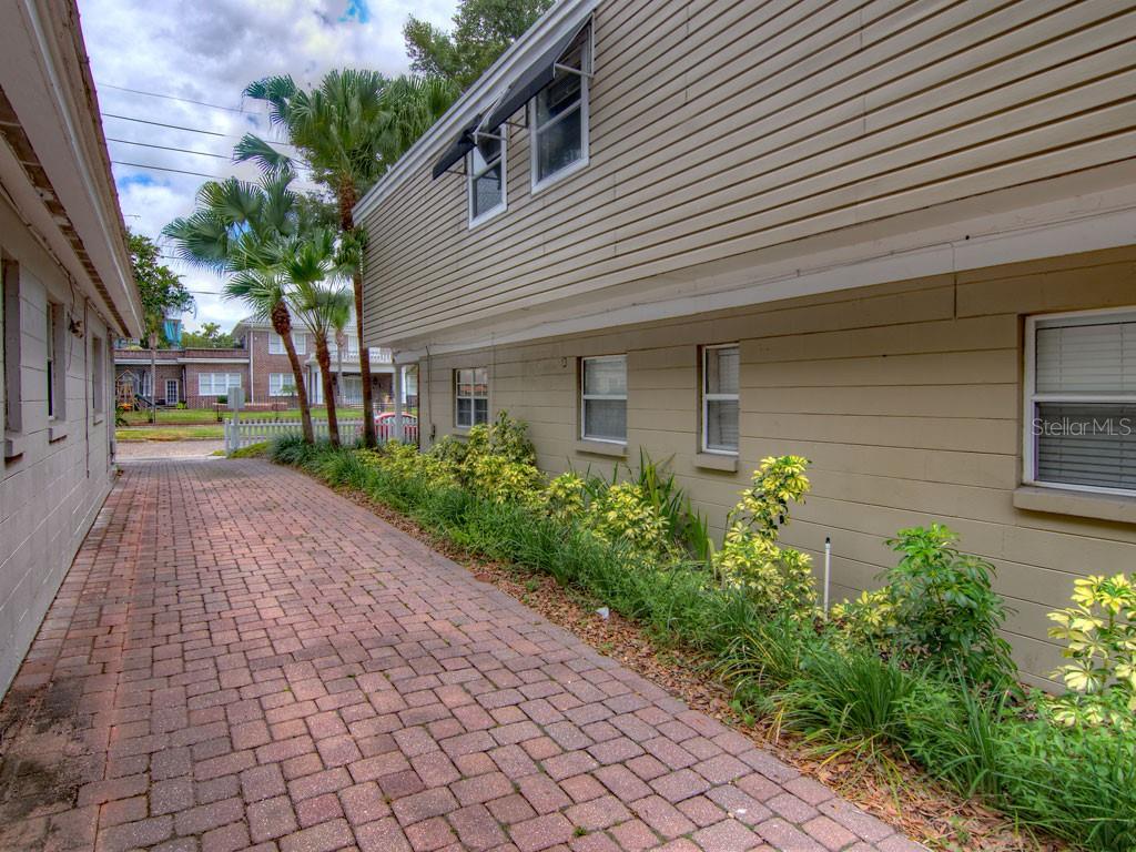 A brick driveway runs alongside a two-story building with beige siding and a landscaped border — 616 PALMER STREET UNIT B, ORLANDO, FL
