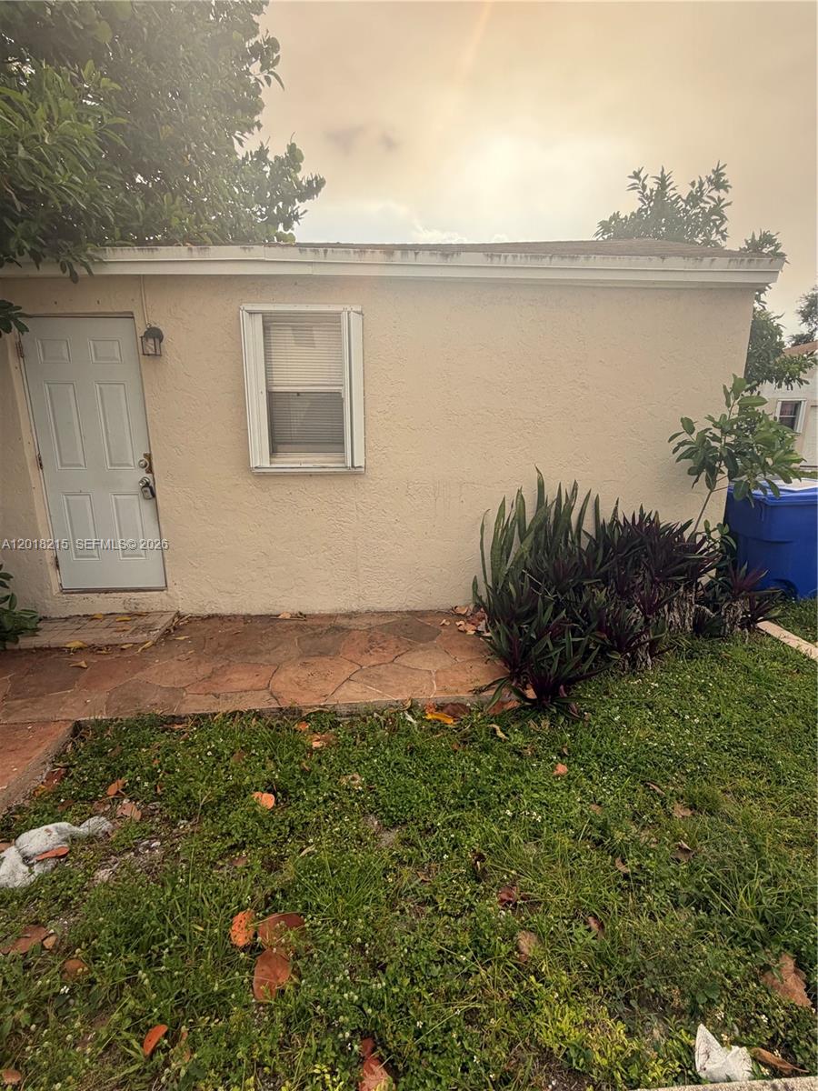 A beige exterior wall features a white door, a single window, and a stone patio — 410 N 58th Ave # 408, Hollywood FL 33021, HOLLYWOOD, FL