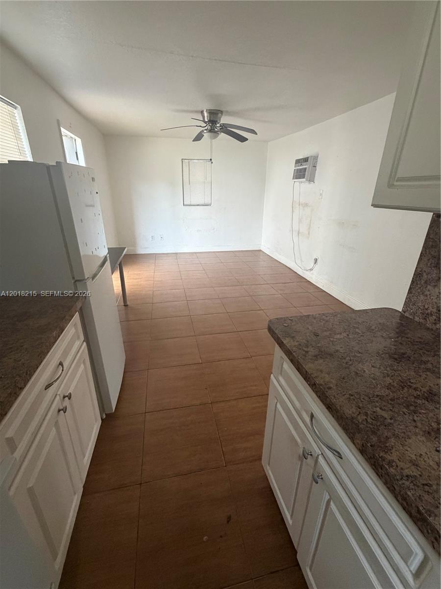 This kitchen features white cabinets, brown countertops, and tile flooring leading into an open area — 410 N 58th Ave # 408, Hollywood FL 33021, HOLLYWOOD, FL