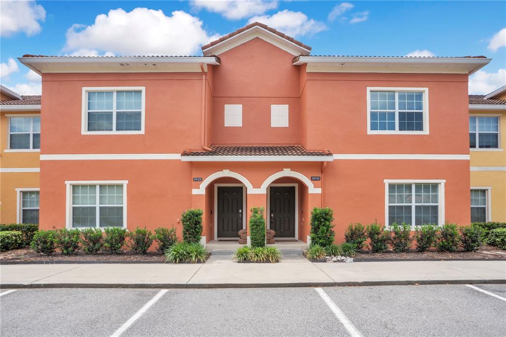 A two-story orange stucco townhouse building features two front doors and a shared concrete walkway — 8928 CUBAN PALM ROAD, KISSIMMEE, FL