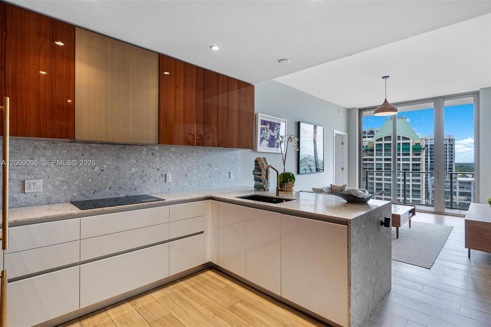 A modern kitchen features white lower cabinets, wood-toned upper cabinets, and a stone-topped island — 2678 Tigertail # 1603, Miami FL 33133, MIAMI, FL