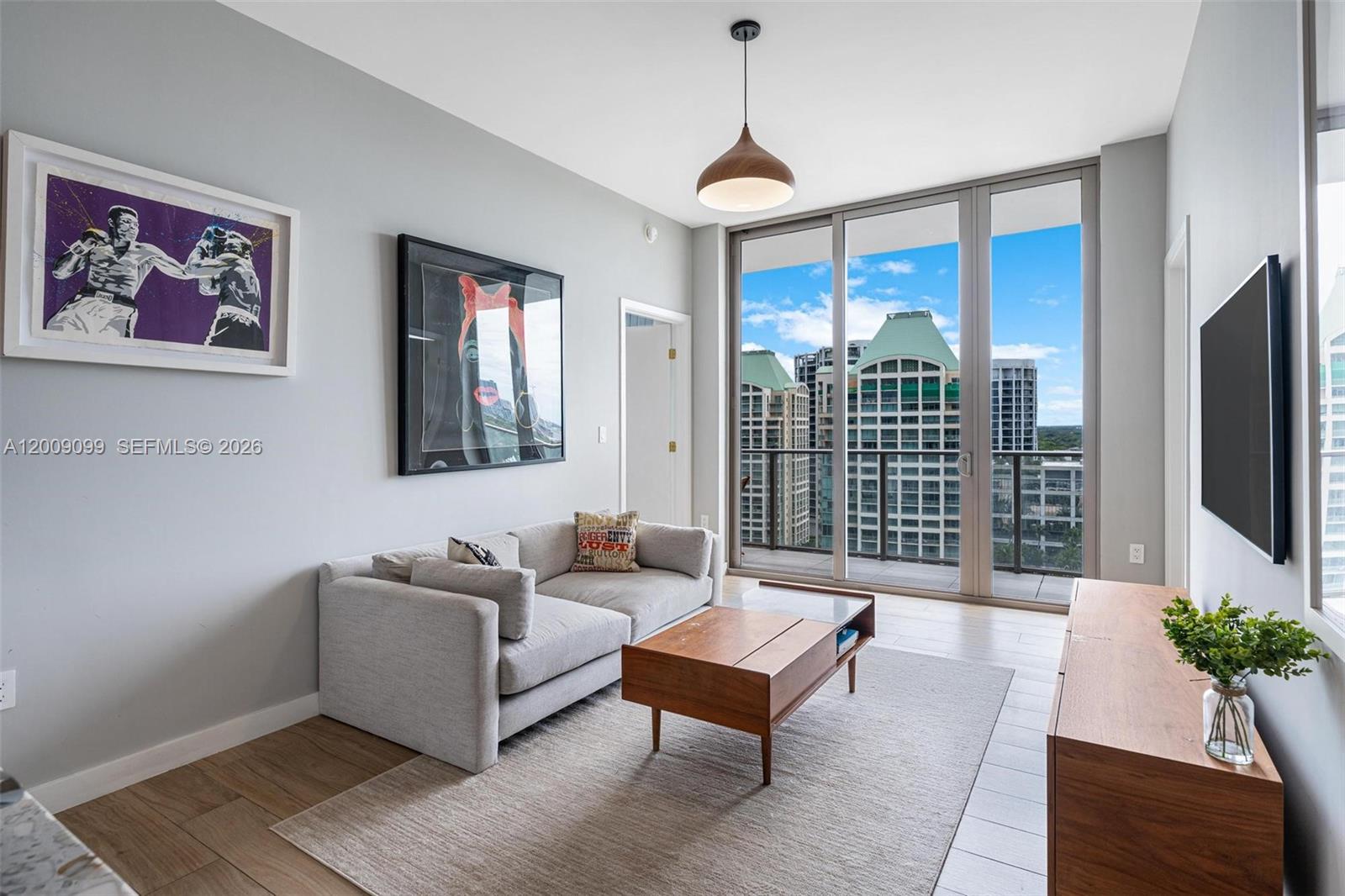 A modern living room features a grey sofa, wooden coffee table, and floor-to-ceiling balcony windows — 2678 Tigertail # 1603, Miami FL 33133, MIAMI, FL