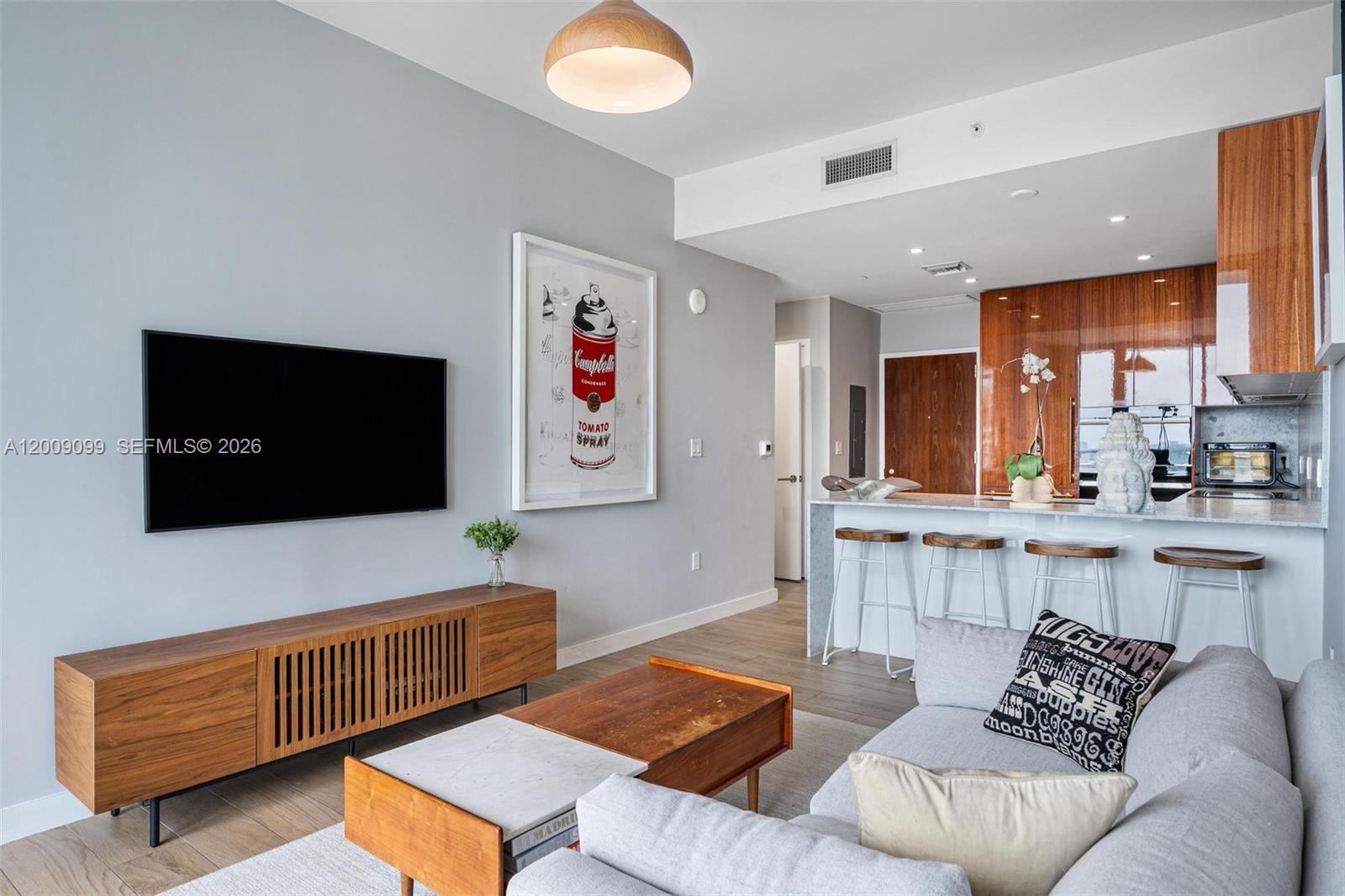 A living room features a flat-screen television, wooden media console, and an open kitchen area — 2678 Tigertail # 1603, Miami FL 33133, MIAMI, FL
