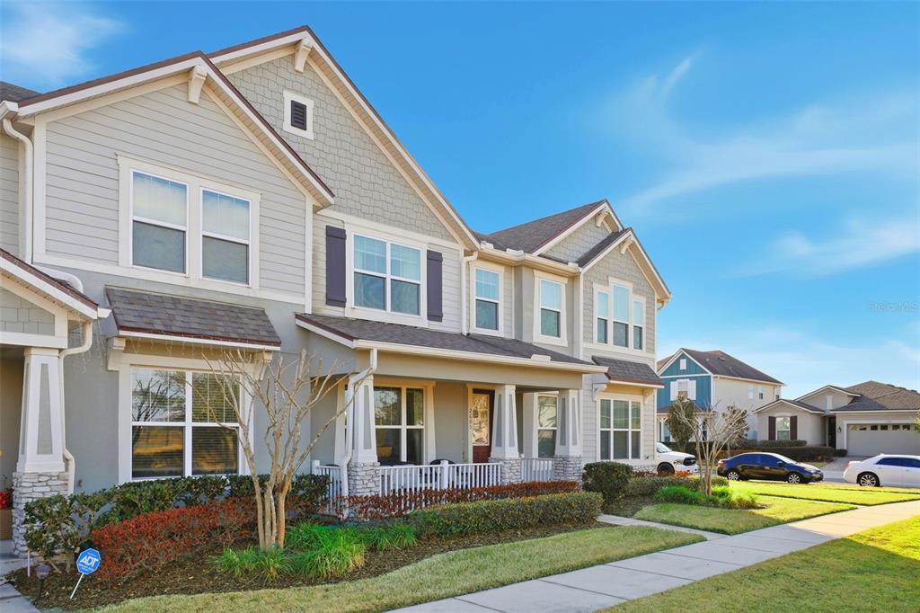 A two-story suburban townhouse with light gray siding, a front porch, and a landscaped yard — 2605 PLAY HARD ALLEY, KISSIMMEE, FL