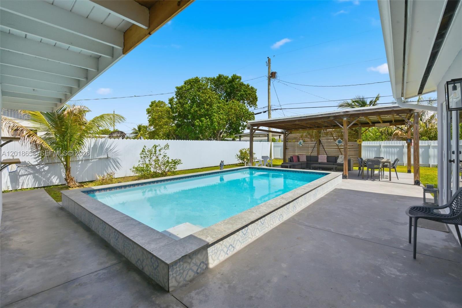 A rectangular above-ground swimming pool sits on a concrete patio next to a covered pergola — 9955 SW 215th St, Cutler Bay FL 33189, CUTLER BAY, FL