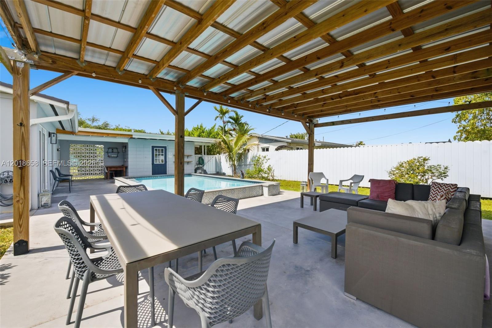 A covered outdoor patio features a dining set, lounge furniture, and an adjacent swimming pool — 9955 SW 215th St, Cutler Bay FL 33189, CUTLER BAY, FL