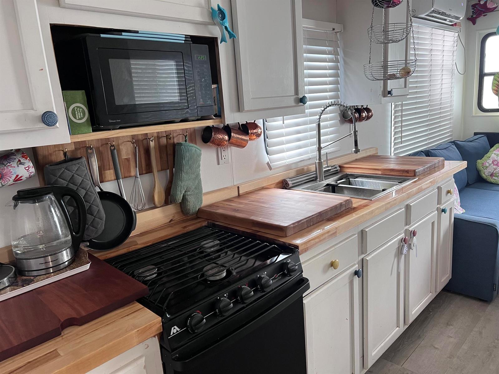 A kitchen with white cabinets, a black stove, a wooden countertop, and a stainless sink — 1801 N Roosevelt Boulevard N, Key West FL 33040, KEY WEST, FL
