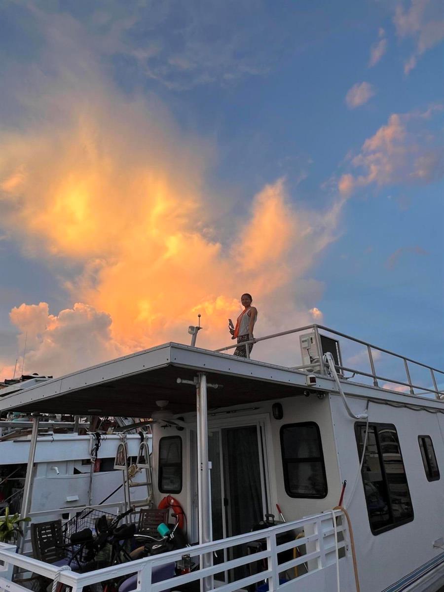 A person stands on the upper deck of a white houseboat under a sunset sky — 1801 N Roosevelt Boulevard N, Key West FL 33040, KEY WEST, FL