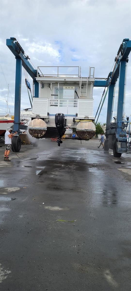 A boat is being pressure washed while suspended by a large mobile boat hoist — 1801 N Roosevelt Boulevard N, Key West FL 33040, KEY WEST, FL