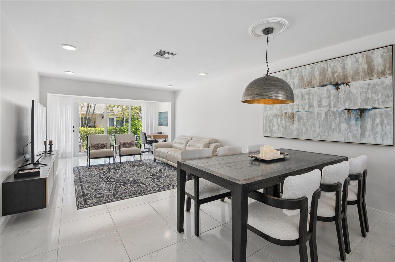 A bright open-concept living and dining area with white tile floors and a large painting — 13725 Flora Place # C, Delray Beach FL 33484, DELRAY BEACH, FL