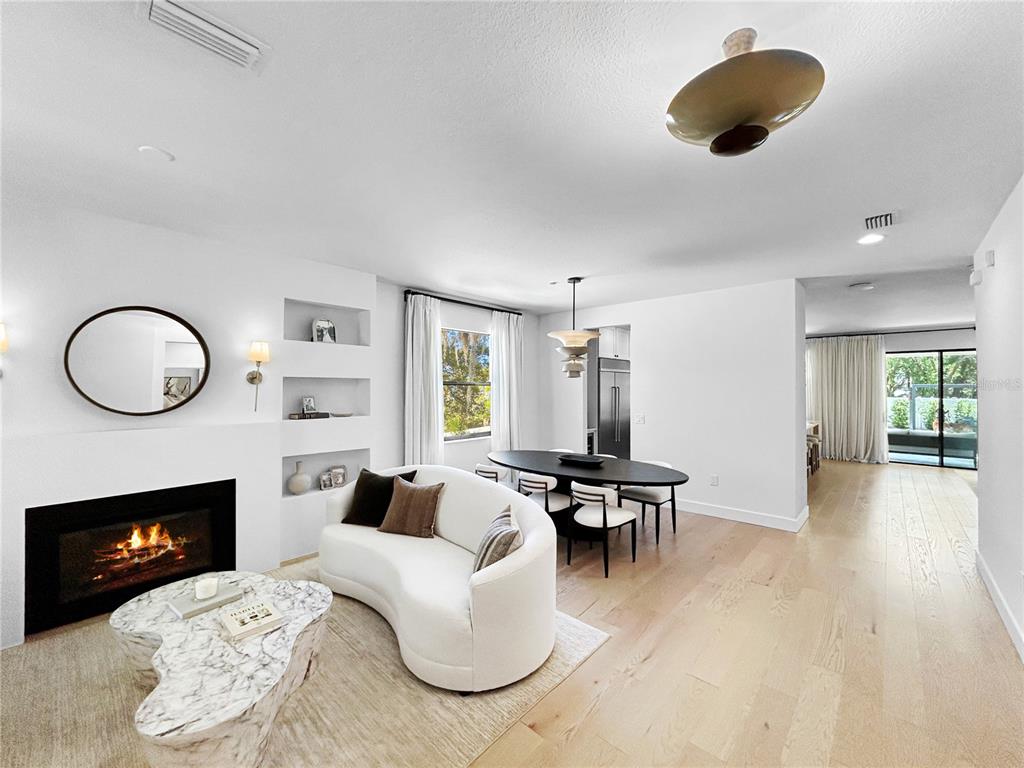 A living and dining area features a fireplace, curved sofa, marble coffee table, and hardwood floors — 12207 MARJORY AVENUE, TAMPA, FL