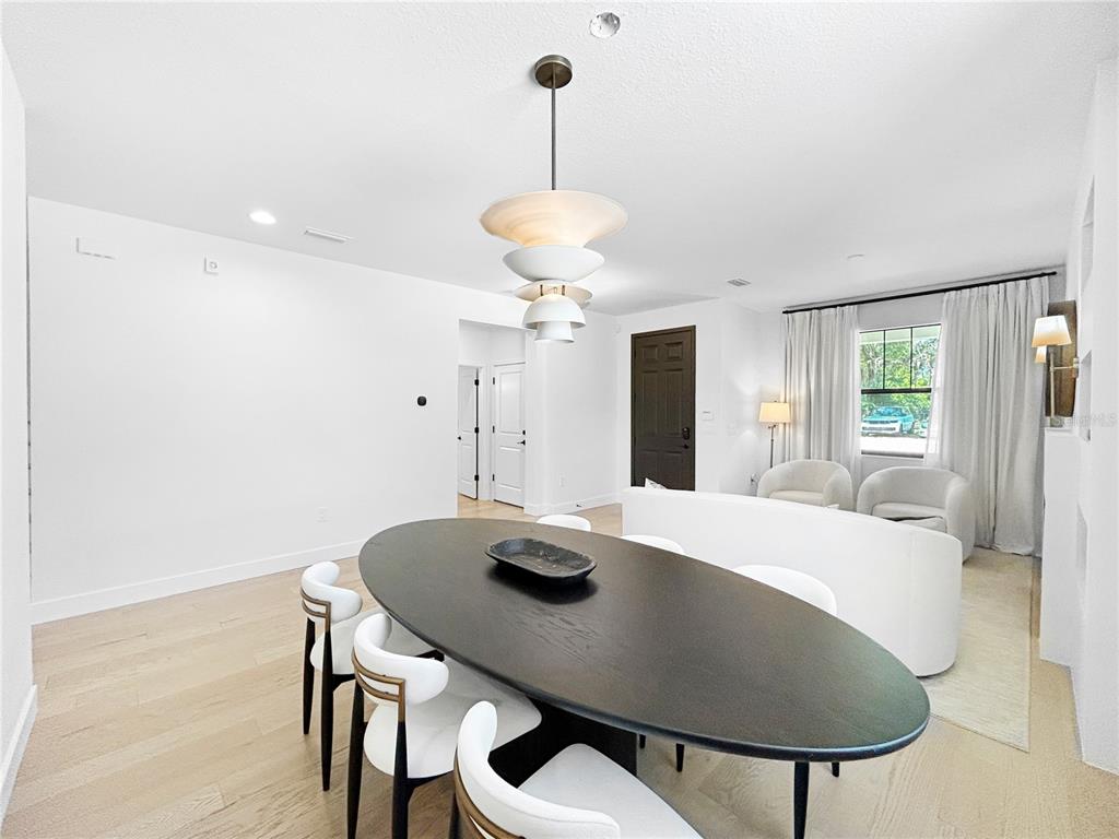 A dining area with a dark oval table and modern pendant light leads to a living room — 12207 MARJORY AVENUE, TAMPA, FL