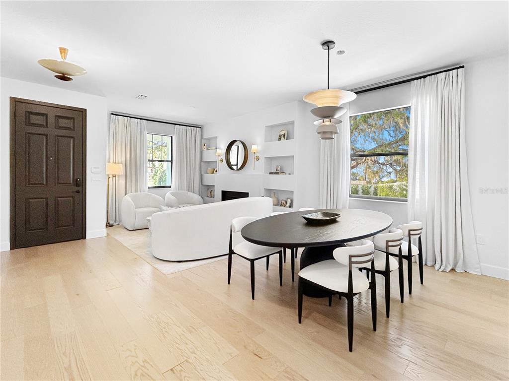 A bright, open-concept living and dining area features light wood floors and white built-in shelving — 12207 MARJORY AVENUE, TAMPA, FL