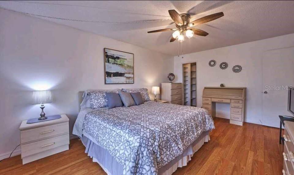 A bedroom with a ceiling fan, a bed, a desk, and wood-look flooring — 4550 COVE CIRCLE UNIT 808, ST PETERSBURG, FL