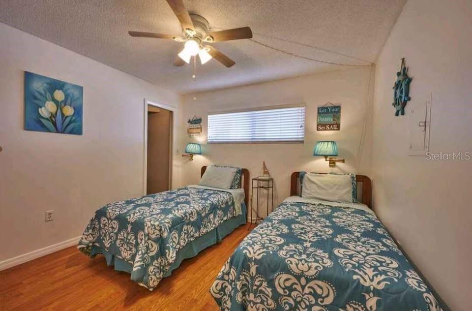 A bedroom features two twin beds with blue patterned bedding, wall sconces, and a ceiling fan — 4550 COVE CIRCLE UNIT 808, ST PETERSBURG, FL