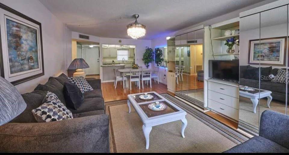A living room with a gray sofa, coffee table, and mirrored wall storage units — 4550 COVE CIRCLE UNIT 808, ST PETERSBURG, FL