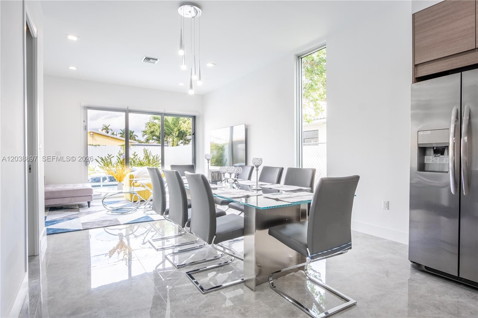 A modern dining room features a glass table, gray chairs, and large sliding glass doors — 3461 SW 25th St # B, Miami FL 33133, MIAMI, FL