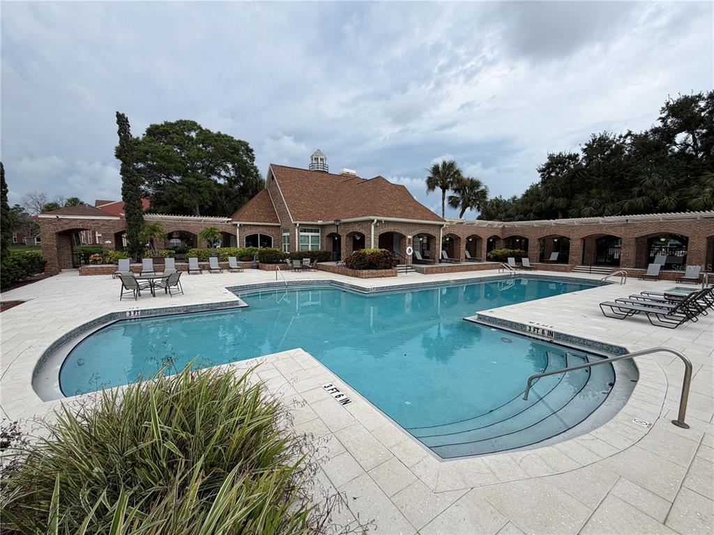 A swimming pool with a surrounding patio and a brick building in the background — 10200 GANDY BOULEVARD N UNIT 1316, ST PETERSBURG, FL