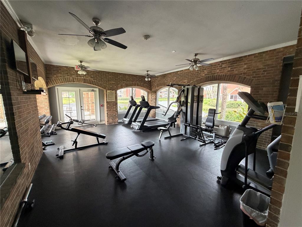 A gym with brick walls, ceiling fans, rubber flooring, and various exercise equipment — 10200 GANDY BOULEVARD N UNIT 1316, ST PETERSBURG, FL