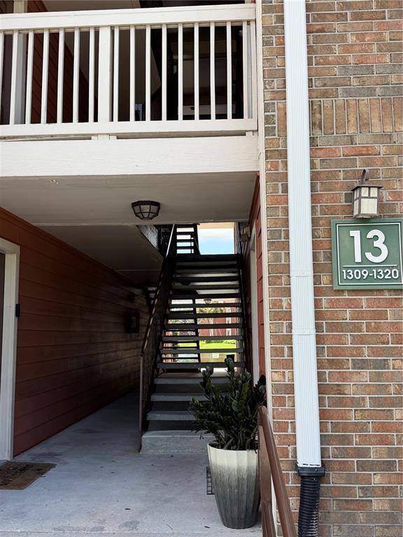 An exterior view shows a brick building with a staircase leading to an upper level — 10200 GANDY BOULEVARD N UNIT 1316, ST PETERSBURG, FL