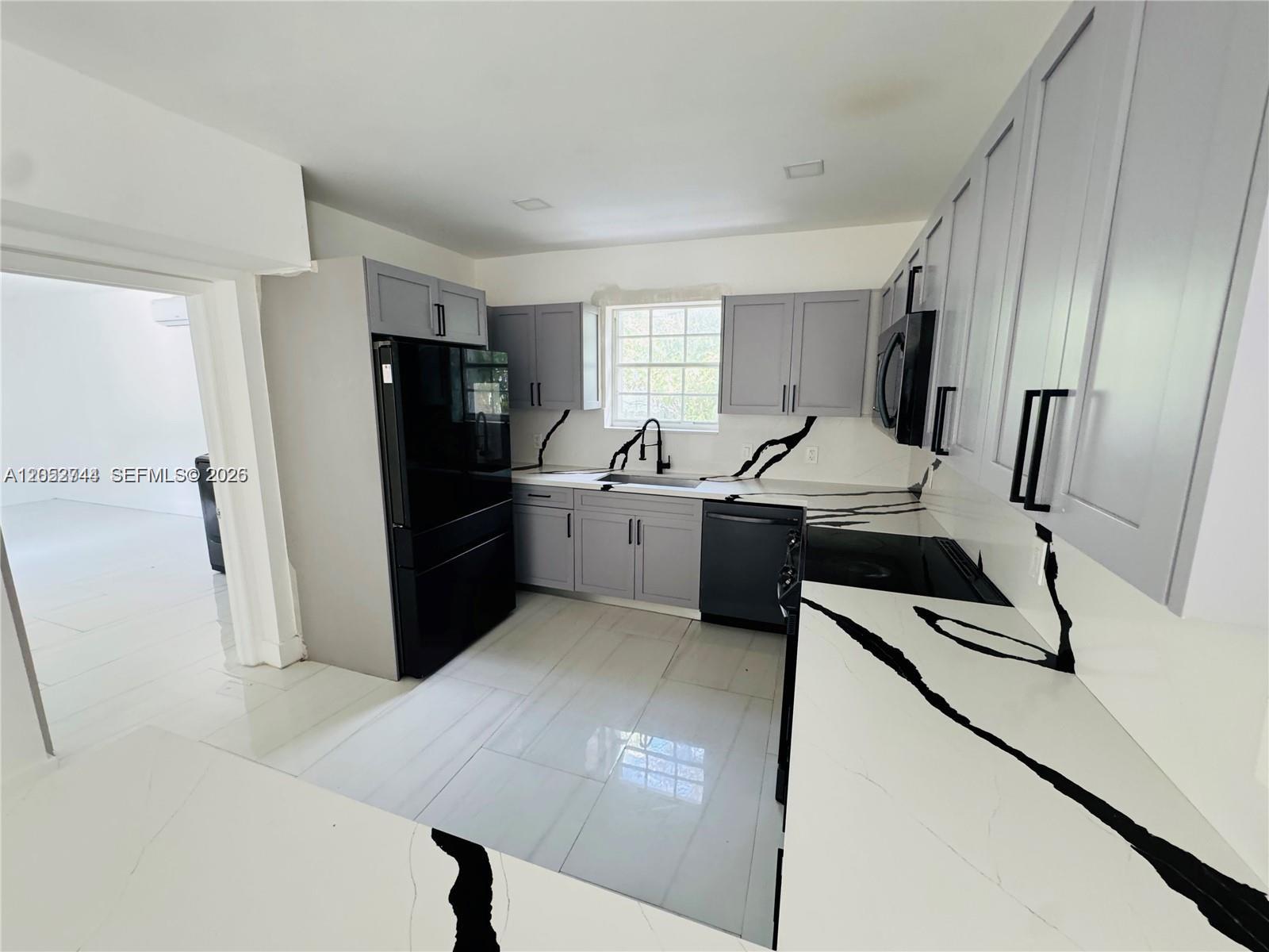 A kitchen features gray cabinets, black appliances, and white countertops with bold black veining — 516 La Villa Dr, Miami Springs FL 33166, MIAMI SPRINGS, FL