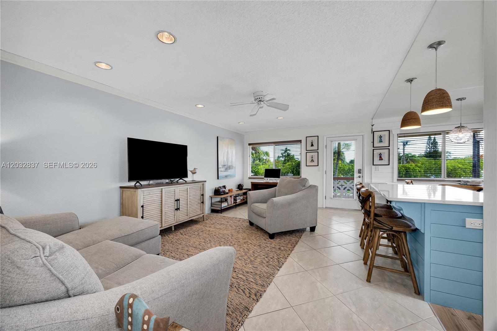 A living room features a light blue kitchen island, gray sofa, and tile flooring — 1050 SW 11th ST # 20L, Hallandale Beach FL 33009, HALLANDALE BEACH, FL